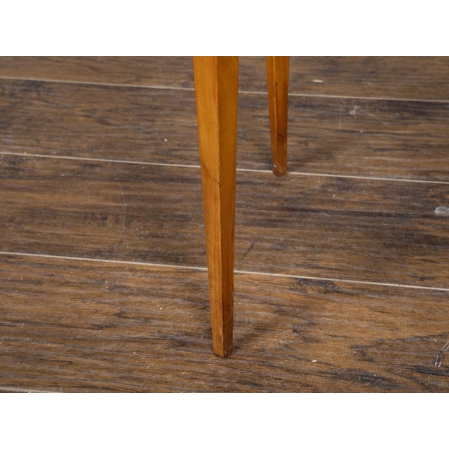 A French Neoclassical style walnut side table from the 19th century, with almond shaped top, ebonized accents and tapered...