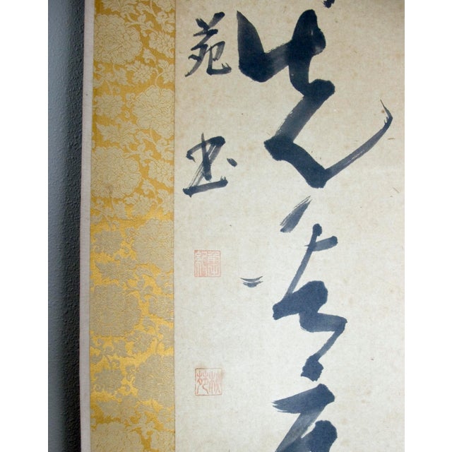 Japanese calligraphy scroll in a bold sosho style, signed with three red seal marks. Ink on paper mounted on a red gold...