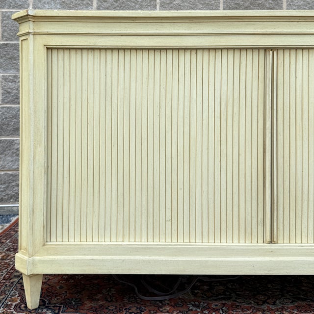 A vintage Baker Furniture Neoclassical style tambour door credenza in distressed toupe. The right cabinet can support...