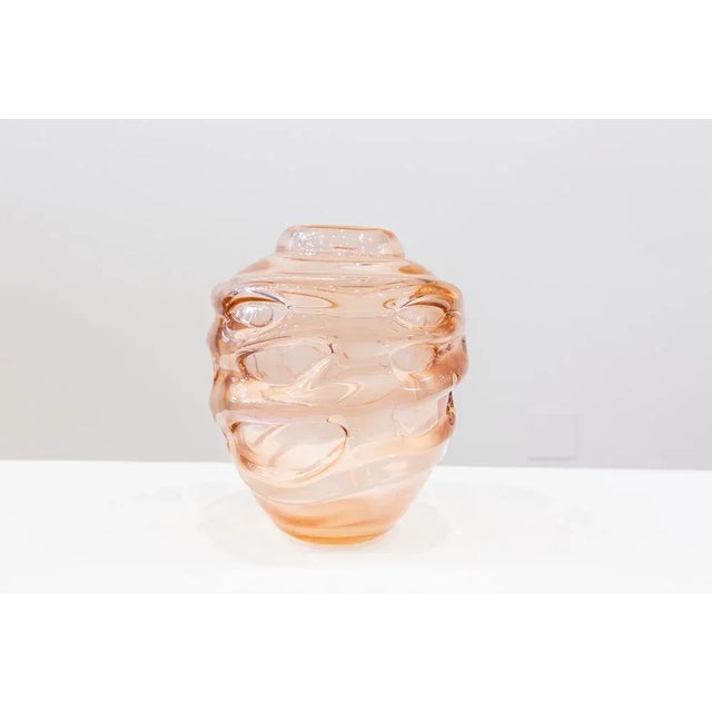 Narrow and low neck globular vase, made of pink transparent glass with relief in the form of irregular drops traveling the...