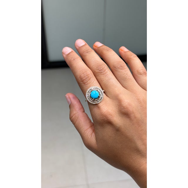 This halo cocktail ring features a 1.52 carat natural turquoise, set in 14K yellow gold. The center stone measuring 8 mm,...