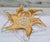 A striking amber and clear art glass centerpiece bowl featuring a dramatic six-point starburst silhouette. Warm honey-...