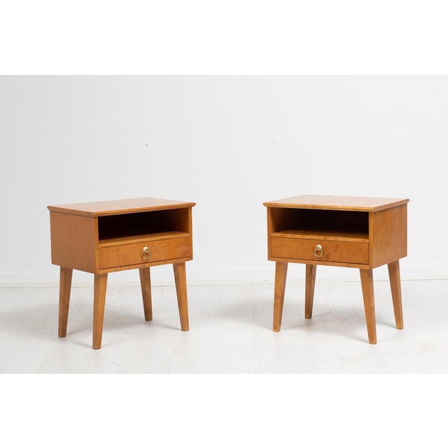 Swedish Art Deco nightstands from the 1920s. The pair are made in light, Swedish birch with a lovely dynamic look to the...