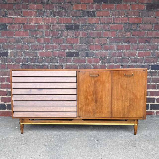 Mid-Century Modern credenza designed by Merton Gershun for American of Martinsville, featuring a warm wood case, brass-...