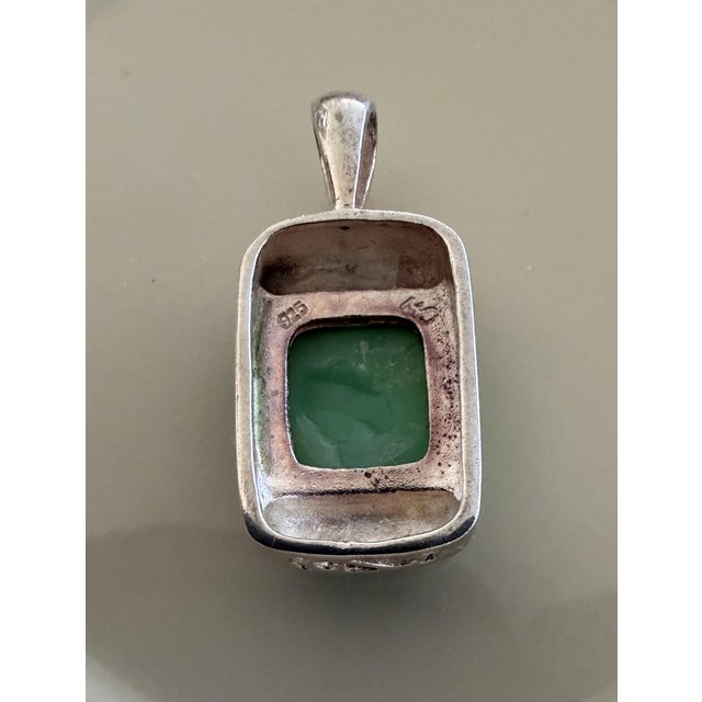 The center stone is a rectangular cabochon, characterized by a smooth, polished, rounded surface without facets Marcasite...