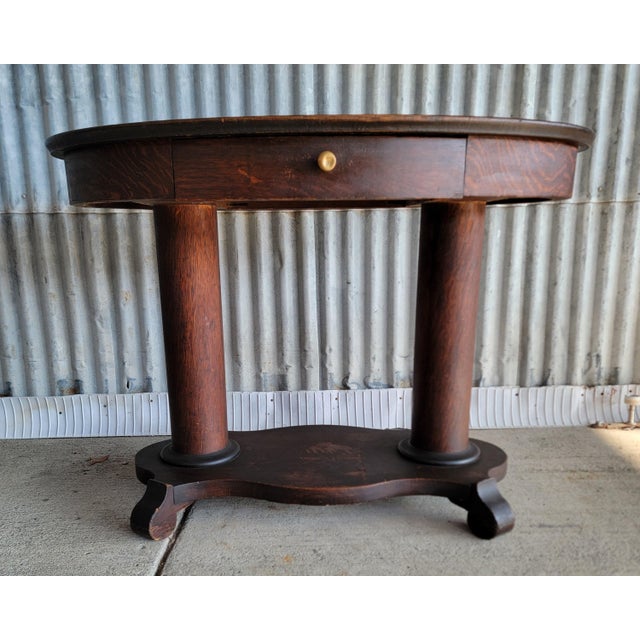 An oval library table / desk from the "Golden Oak" era of American furniture design. Made with quarter-sawn, often called...
