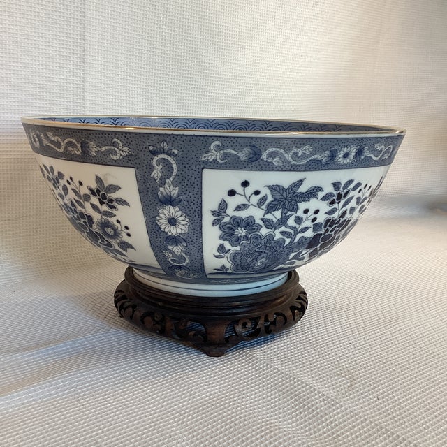 Blue and white floral motif Chinoiserie bowl with wooden stand for display. Blue glaze on white ceramic with gold rim...