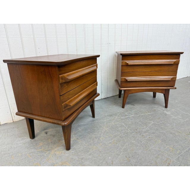 These Mid-Century United walnut nightstands offer a striking blend of sculptural detail and timeless craftsmanship....