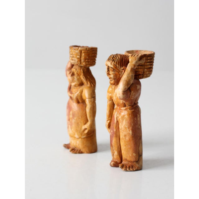 A charming pair of vintage Latin American folk art figures, depicting a man and woman carrying woven baskets atop their...