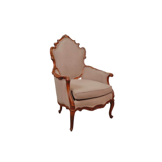 A hand carved Rococo bergere armchair circa 1890. The solid frame is elegantly carved with serpentine curves, detailed...