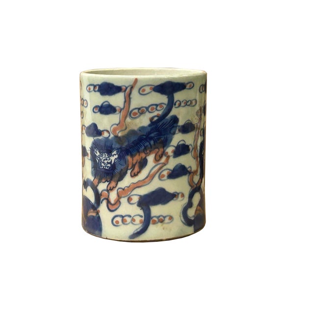 This finely potted cylindrical ceramic brush pot features a dynamic underglaze blue and iron-red painted design depicting...