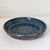 Signed handmade studio pottery draining dish or berry bowl featuring a rich mottled blue glaze with earthy undertones and...