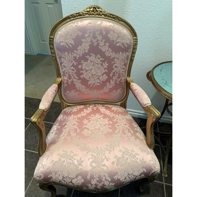 This elegant pair of chairs features a classic French Provincial design with a gilded wooden frame and soft, floral damask...