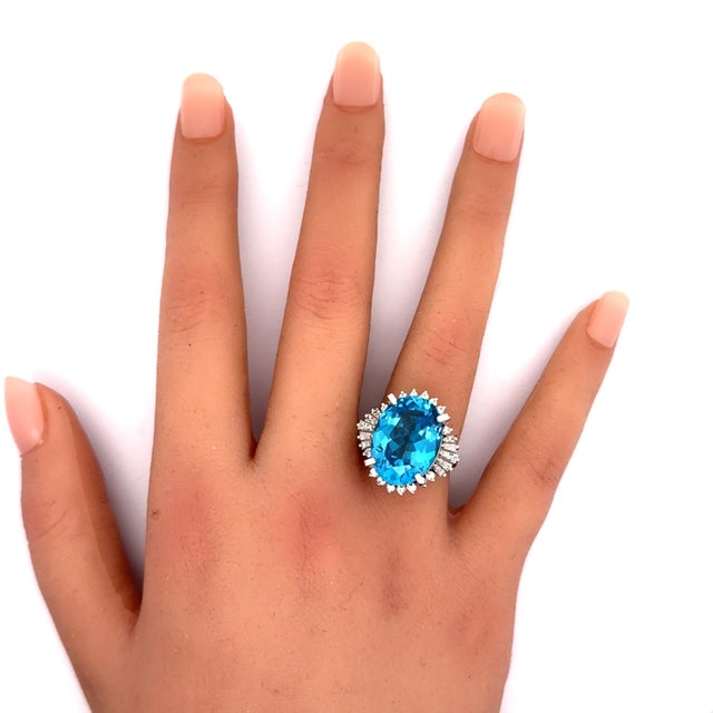 A contemporary fashion ring featuring a 14.16 carat oval-cut blue topaz as its centerpiece. The vibrant blue hue of the...