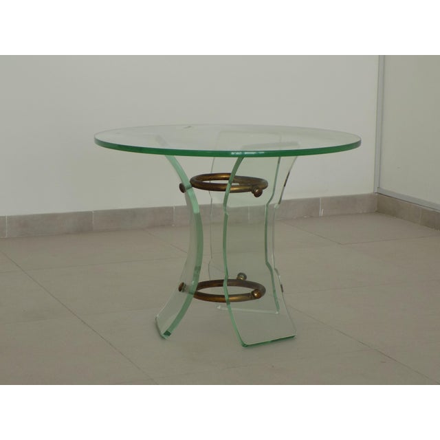 Glass coffee table with a brass frame and thick glass top, with three curved glass legs shaped by grinding. Produced by...