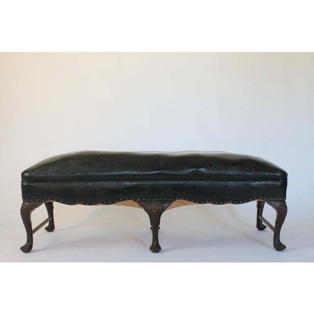 Antique English Georgian style hand-carved ornate low wood bench with black leather upholstery and brass nail head trim....