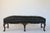 Antique English Georgian style hand-carved ornate low wood bench with black leather upholstery and brass nail head trim....