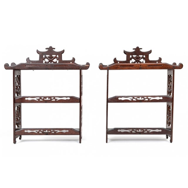 A pair of Chinoiserie-style carved wood wall display shelves with pagoda-form crest sand openwork scrolling foliate side...