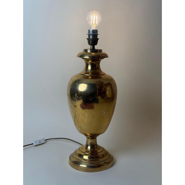 This monumental italian table lamp was crafted from exceptionally heavy solid brass during the 1970s. Its elegant urn-...