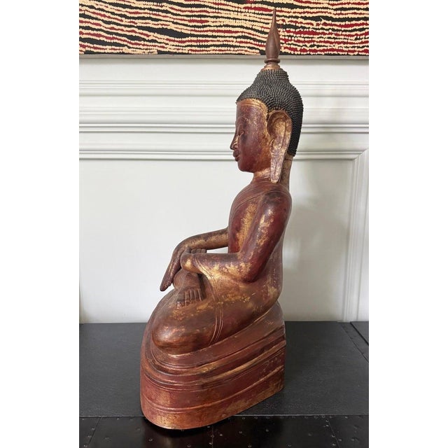 A gilt lacquer wood Buddha statue from Burma, circa 19th century. The Buddha is depicted seating on a plinth throne in an...