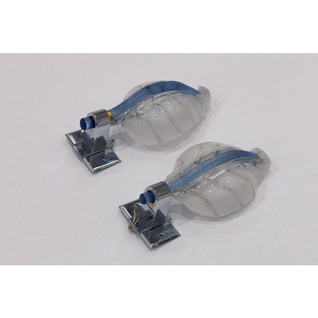 A pair of handmade glass leaf sconces with white and blue glass. A beautiful pop of color to any living setting.