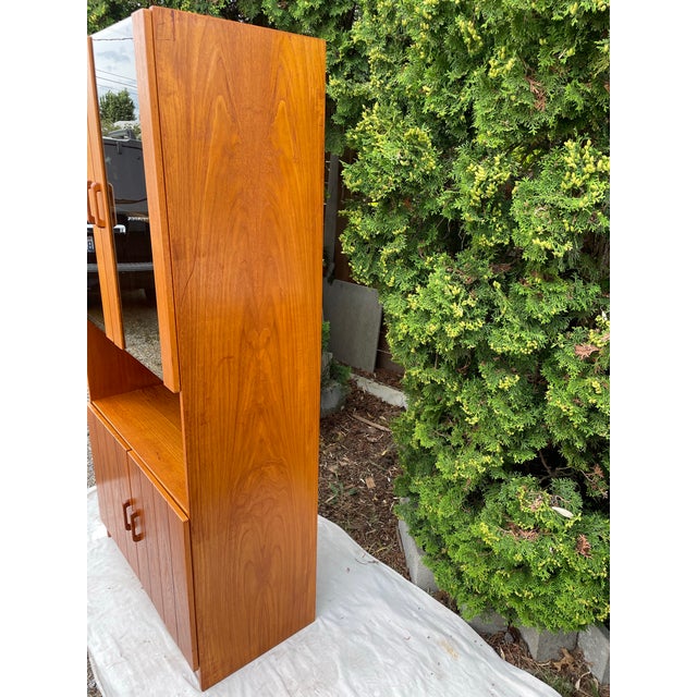 A tall Danish Modern teak cabinet with smoked glass display area. The cabinet features a lower enclosed portion with...
