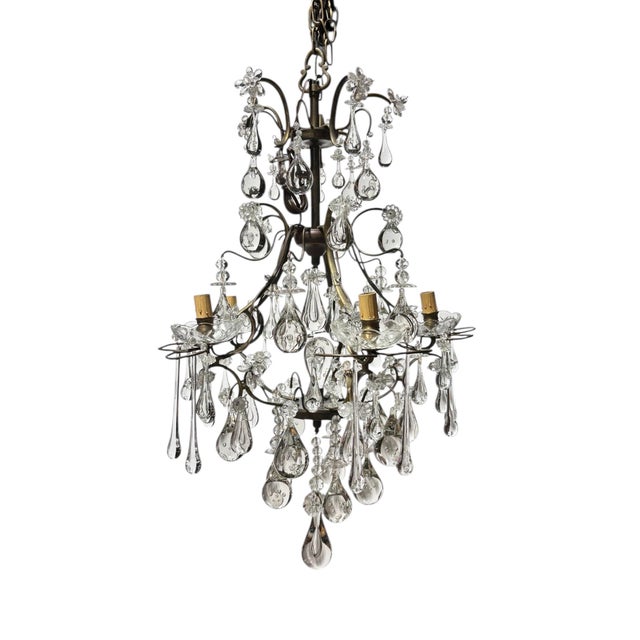 A brass and glass chandelier dating from the early 1800's. The elegant frame supports hand blown glass droplets and glass...