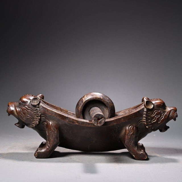 This is a finely crafted antique bronze herb grinder featuring a unique double tiger head design. The piece consists of a...