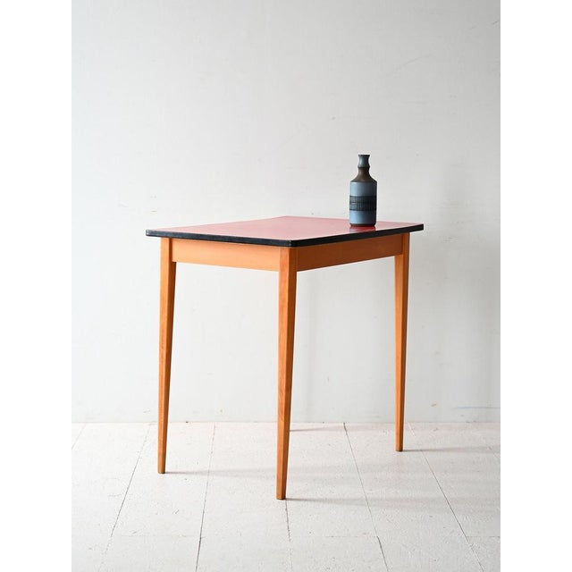Scandinavian table from the 1960s with tapered wooden legs and red formica top with contrasting black edge. Vintage...
