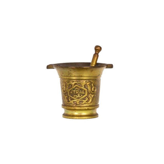 Solid bronze mortar and pestle set from the 20th century, featuring raised scrollwork and the embossed “ATRAL”...