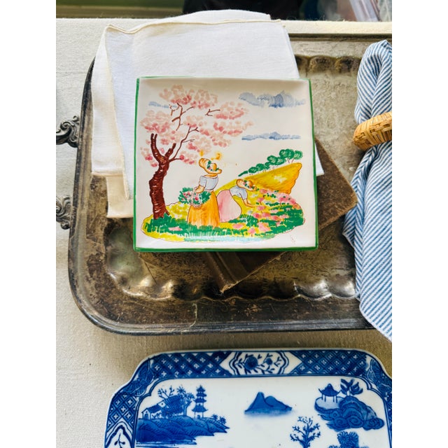 A lovely hand-painted Italian ceramic wall plate depicting a soft spring countryside scene, with flowering trees, rolling...