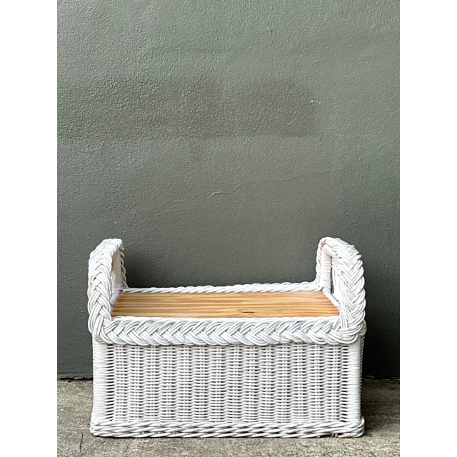 A vintage braided white rattan ottoman with a sturdy woven construction, crisp white finish, and decorative braided edging...