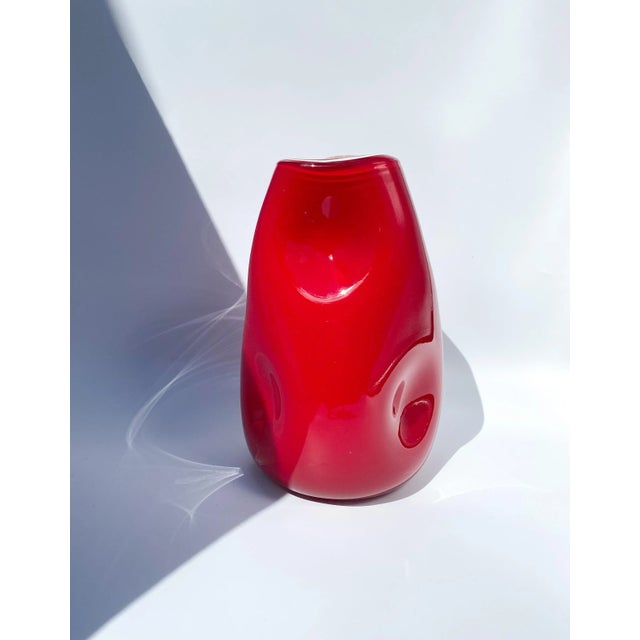 Unique 10" tall hand blown cased glass dimple vase with pinched organic curvature. The outer color is a rich blood red...