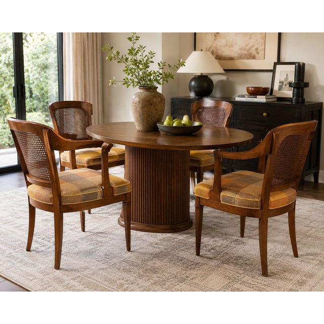 A stylish set of four vintage dining chairs by Henredon featuring elegant cane backs, sculptural walnut-toned frames, and...