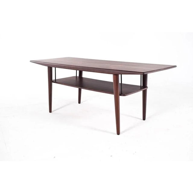 Elegant rectangular rosewood coffee table. with a shelf supported by four metal supports. Denmark, 1960s. This piece is...