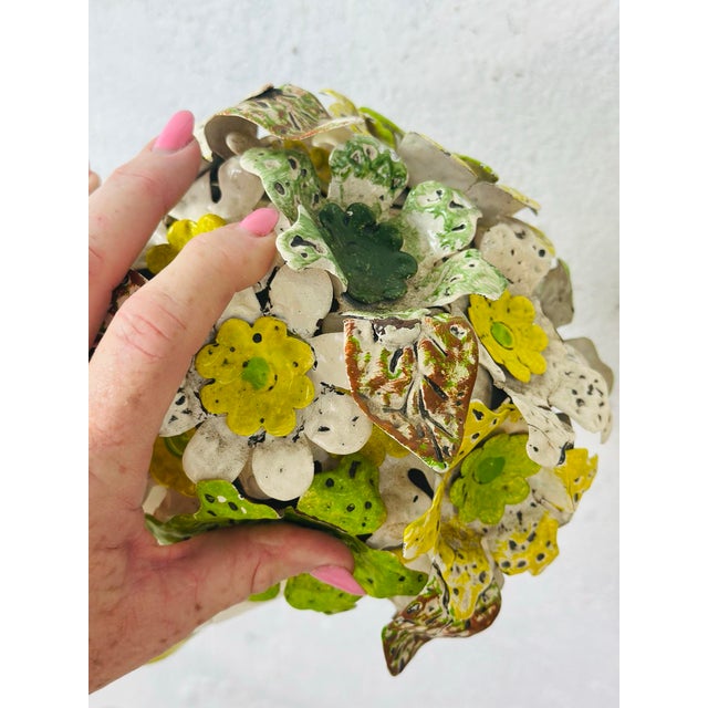 This is a decorative metal toleware floral arrangement in a small painted cachepot. The bouquet is composed of layered,...