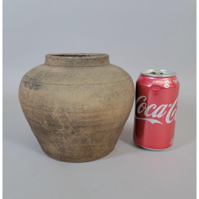 A finely potted Chinese earthenware storage jar from the Eastern Han dynasty (c. 25–220 AD), featuring a balanced globular...