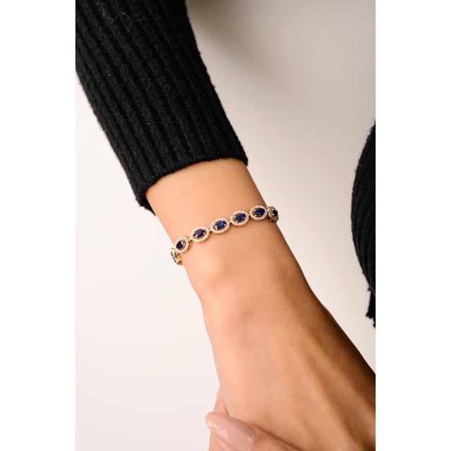 This elegant halo tennis bracelet features 19 oval cut blue sapphires totaling 5.6 carats, set in 14k yellow gold. Each...