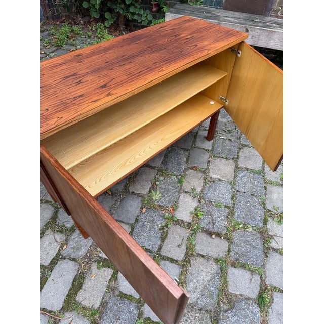 This compact mid-century sideboard from Denmark combines masterful wood craftsmanship with thoughtful functionality. This...