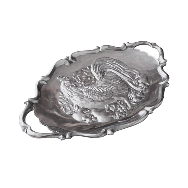 An oval serving platter in pewter, made by Lenox. In the center is an embossed turkey surrounded with foliage and fruit....