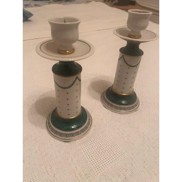 These are decorative porcelain candlesticks featuring a neoclassical column design. It showcases ornate polychrome...