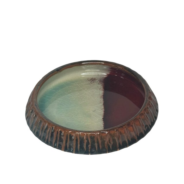 A striking piece of American studio ceramics with an unusually accomplished glaze treatment. The shallow catchall form...
