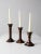 Set of three vintage wooden candlestick holders with turned column forms and brass sockets. Varying heights create an...