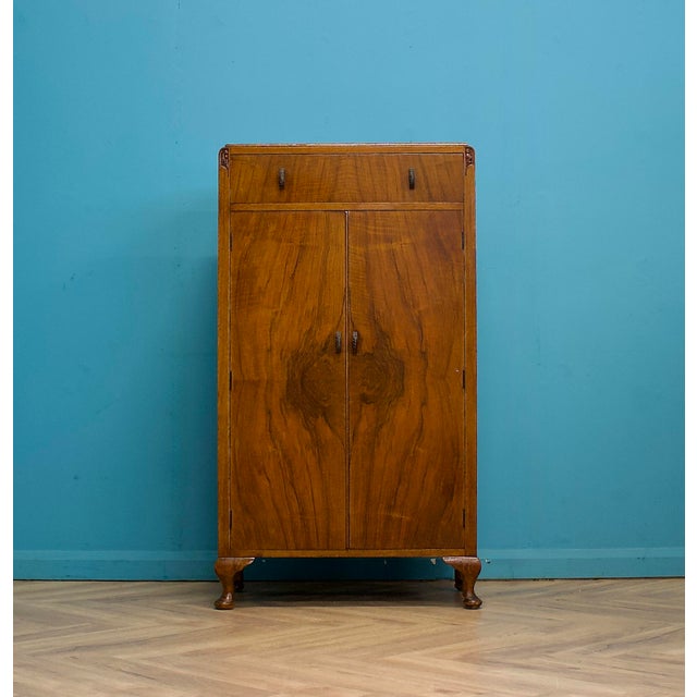 Compact walnut linen cabinet with a drawer over double doors. Inside are fixed shelves for practical storage. The drawer...