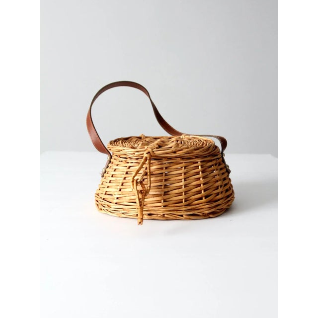 This is a vintage wicker basket with leather strap. The woven basket features a lid closure with woven loop closure.