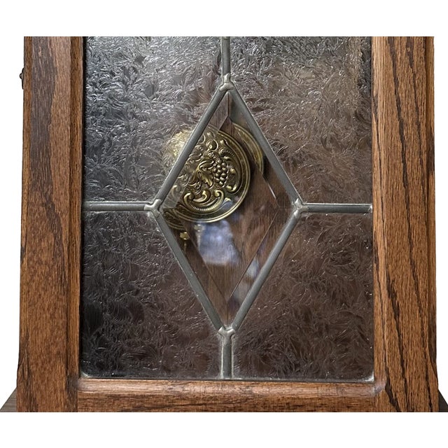 Solid oak cabinet; flat pediment and base; door featuring carved florets in top corners and leaded glass with beveled...