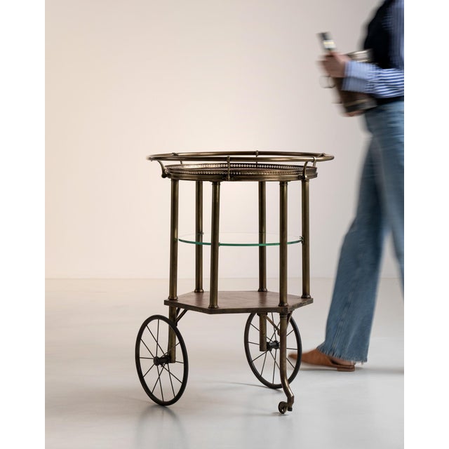 A stylish mid-century bar cart combining a brass frame with glass shelves, reflecting the light and elegant aesthetic of...