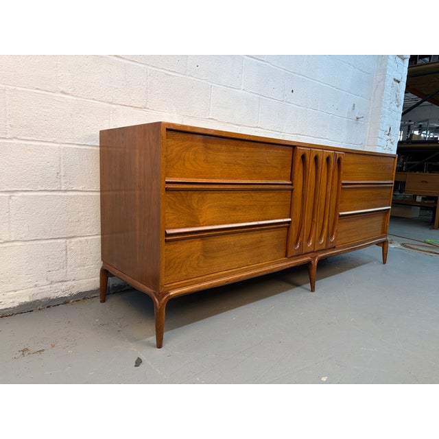 Introduce timeless sophistication to your space with this stunning 1960s Mid-Century sculptural walnut dresser—a perfect...