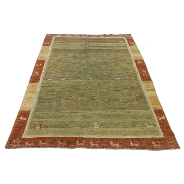 This authentic hand-knotted Gabbeh wool rug features a striking moss and olive green field framed by a terracotta red and...