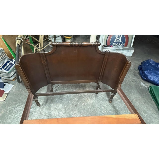 A charming early 20th-century twin bed showcasing elegant curves and finely turned posts. The headboard and footboard...